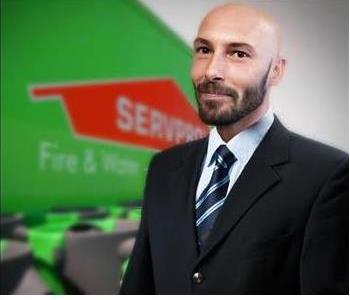 Male employee smiling in front of SERVPRO logo